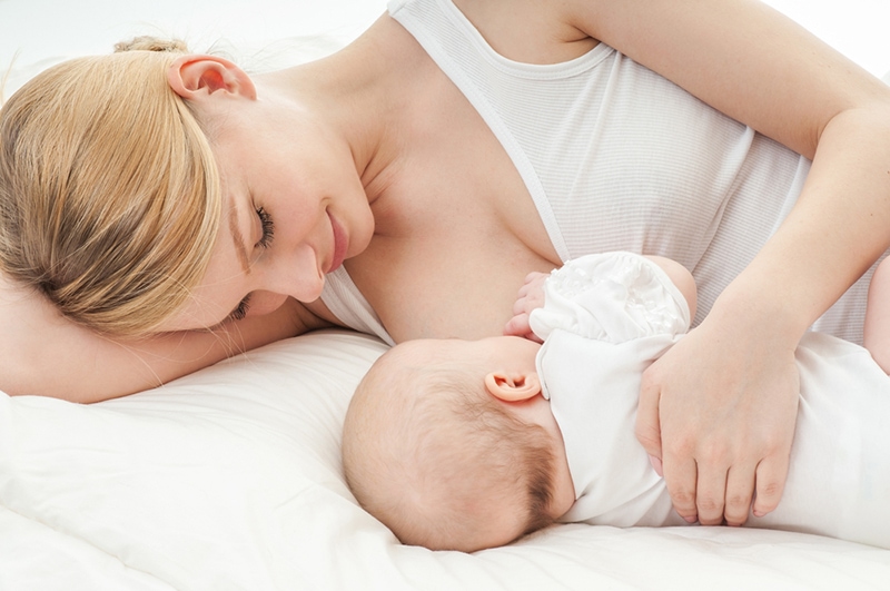 Mutter stillt ihr Baby auf dem Bett