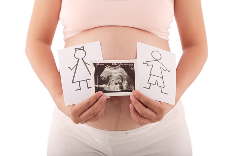 Schwangere Frau mit Ultraschall und Zeichnungen von Jungen und Mädchen