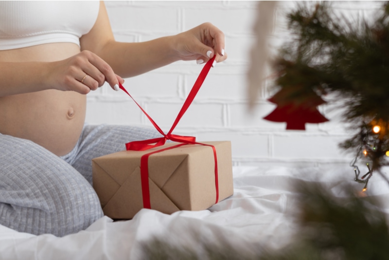 Schwangere, die ein Weihnachtsgeschenk auspacken
