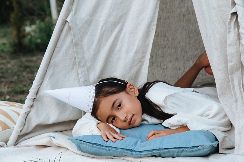 ein kleines Mädchen, das Geburtstag auf einem Kissen in einem Zelt liegt