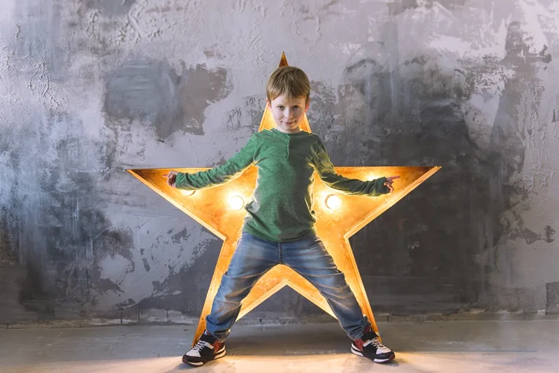 kleiner Junge, der vor einem Licht in Sternform steht