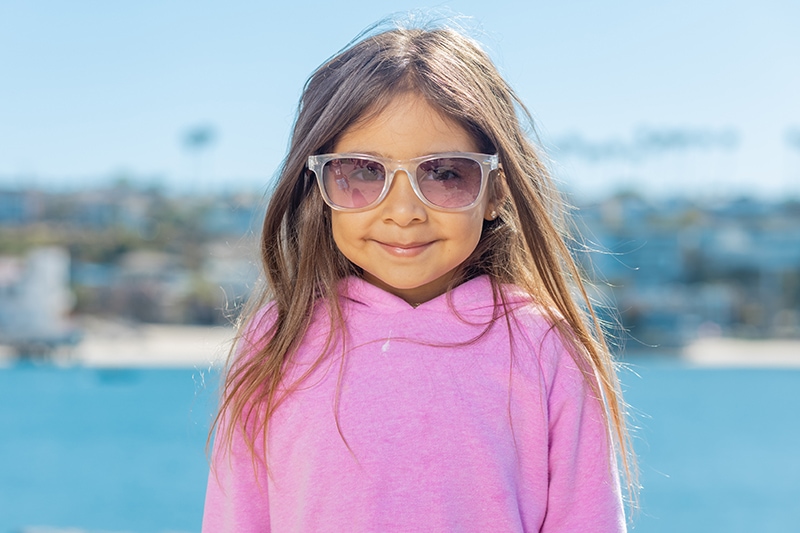 kleines Mädchen in rosa Hoodie mit Sonnenbrille