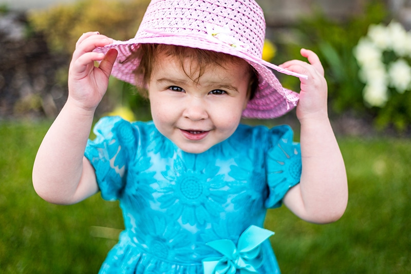 kleines Mädchen mit rosa Hut und blauem Kleid