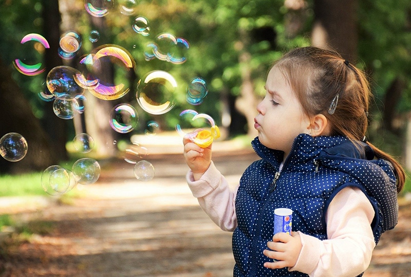 kleines Mädchen spielt mit Seifenblasen im Park