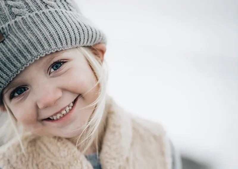 kleines lächelndes Mädchen in grauer Mütze