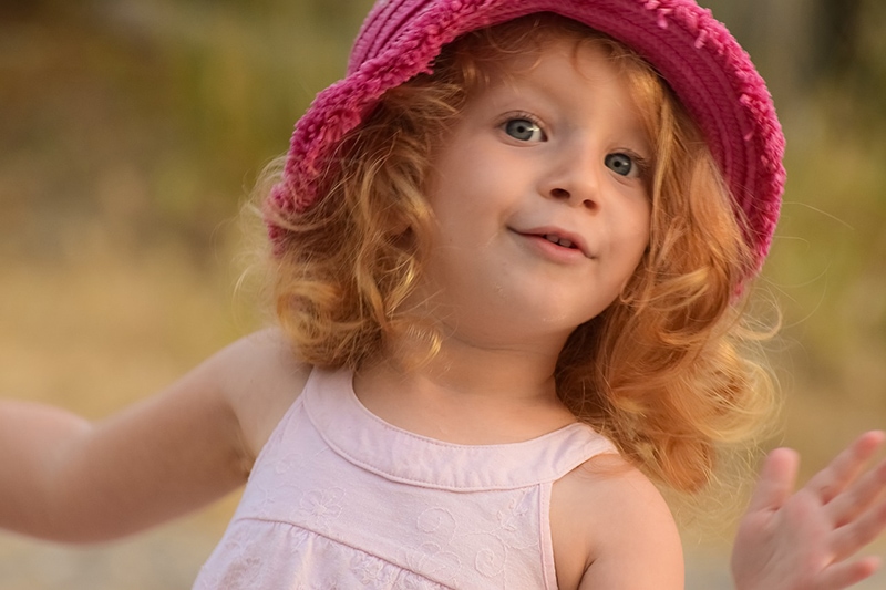 kleines rothaariges Mädchen mit rosa Hut