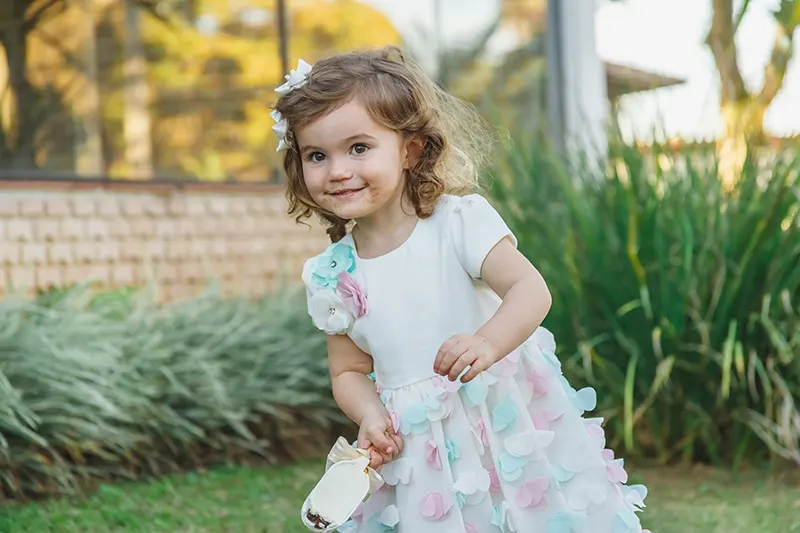 lächelndes kleines Mädchen mit Eis im Hof stehend