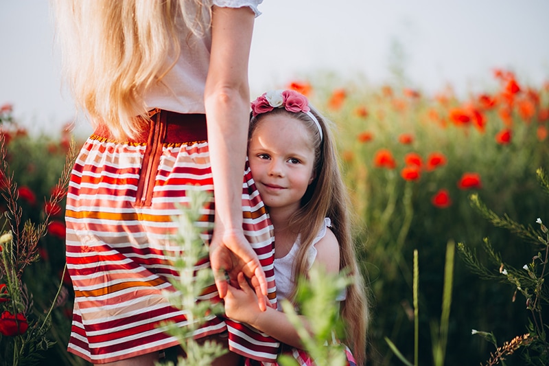 süßes Mädchen Händchen haltend mit ihrer Mutter im Blumenfeld