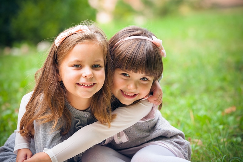 zwei kleine Freundinnen umarmen sich im Park