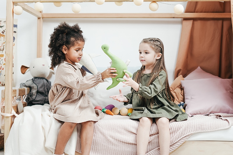 zwei kleine Mädchen spielen mit Spielzeug auf dem Bett