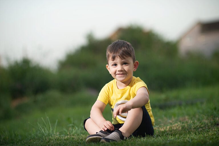 kleiner Junge sitzt im Gras