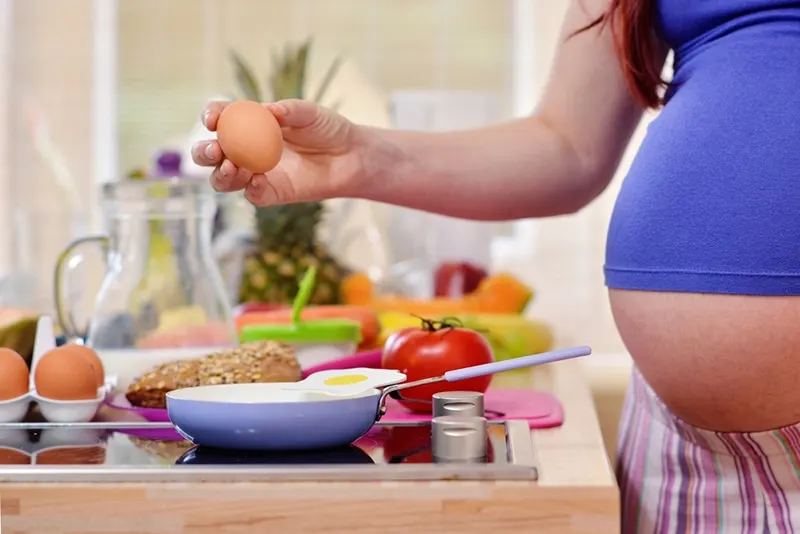 Schwangere bereitet eine Mahlzeit mit Eiern zu