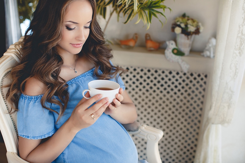 Schwangere ruht sich zu Hause aus und trinkt Tee
