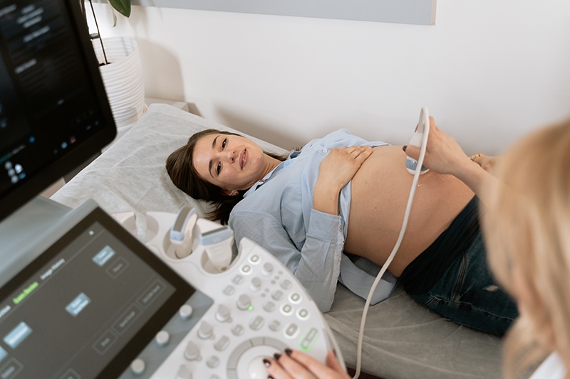 schwangere frau, die während der ultraschalluntersuchung in der arztordination liegt