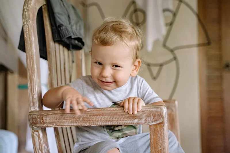 süßer kleiner Junge sitzt im Holzstuhl