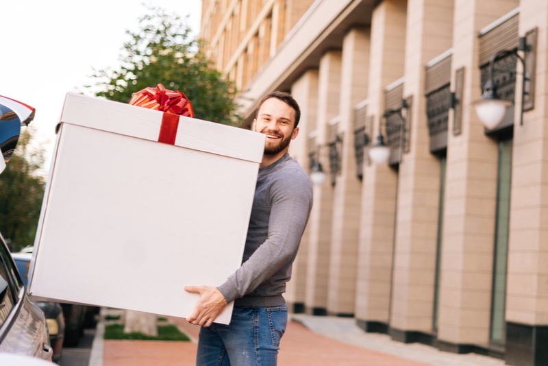 männer, die ein großes geschenk auf der straße halten