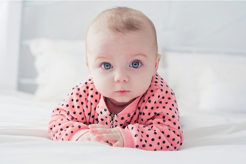 Baby auf dem Bett, das in die Kamera schaut