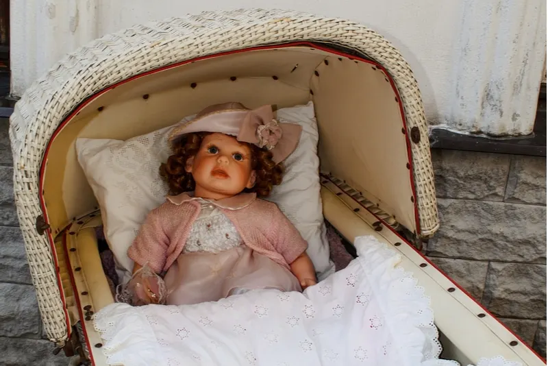 Puppenwagen aus Holz mit Puppe im Inneren