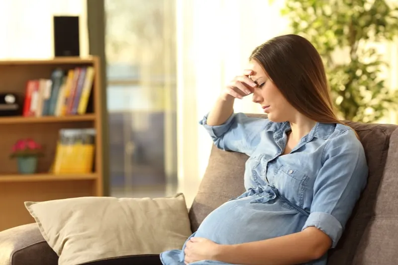 Schwangere Frau mit Schmerzen auf dem Sofa sitzen