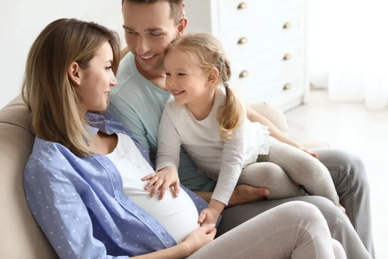 glückliche familie mit schwangerer mutter, die zu hause sitzt