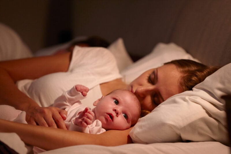 schlafende Mutter mit wachem Neugeborenen von ihr
