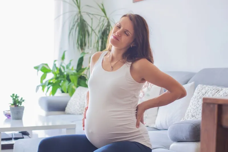 schwangere frau mit rückenschmerzen, die sie zurückhält