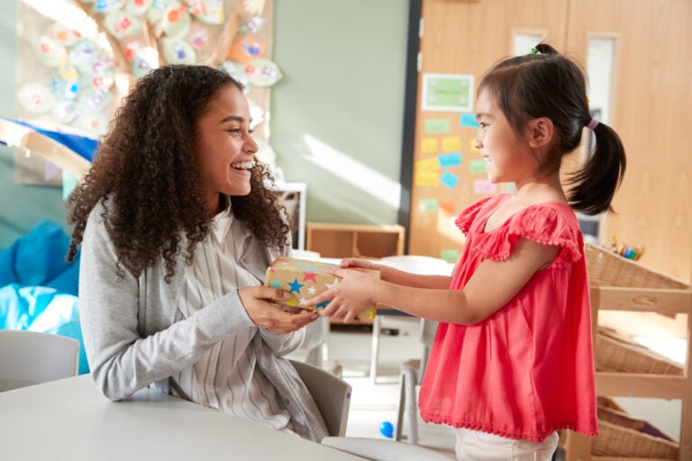 Kleines Mädchen schenkt ihrer Kindergärtnerin ein Geschenk