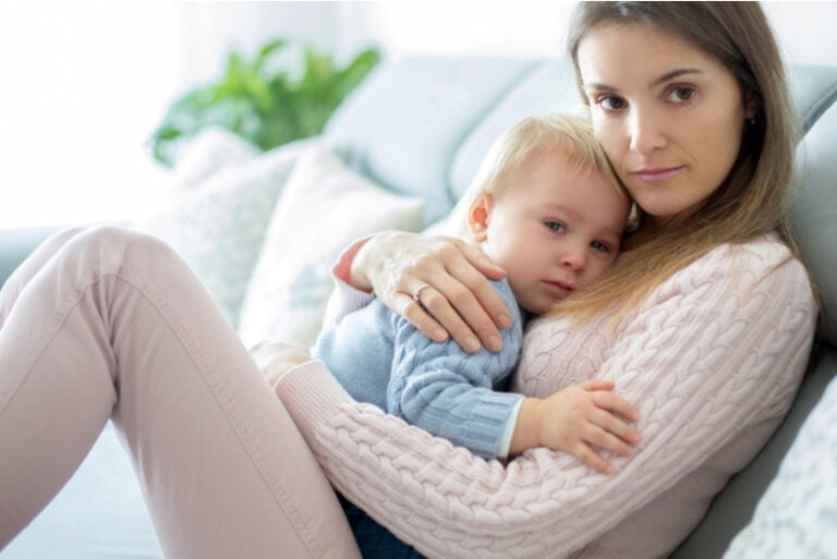 Junge Mutter beruhigt ihr Baby im Arm