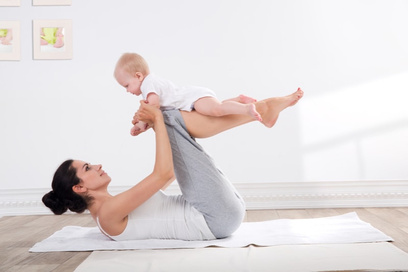 Frau trainiert mit ihrem Baby zu Hause