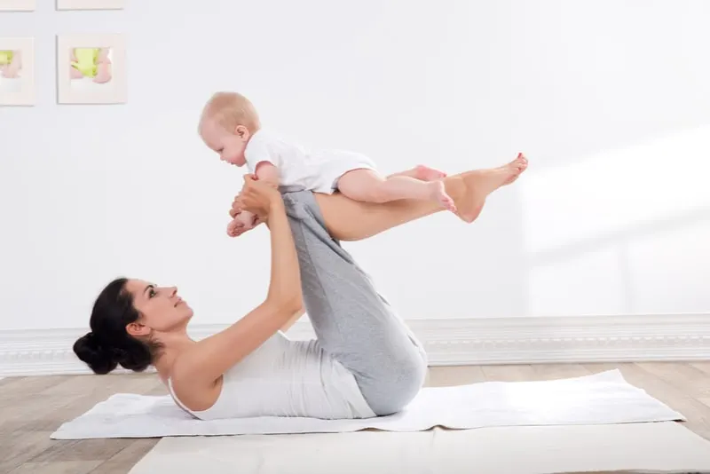 Frau trainiert mit ihrem Baby zu Hause