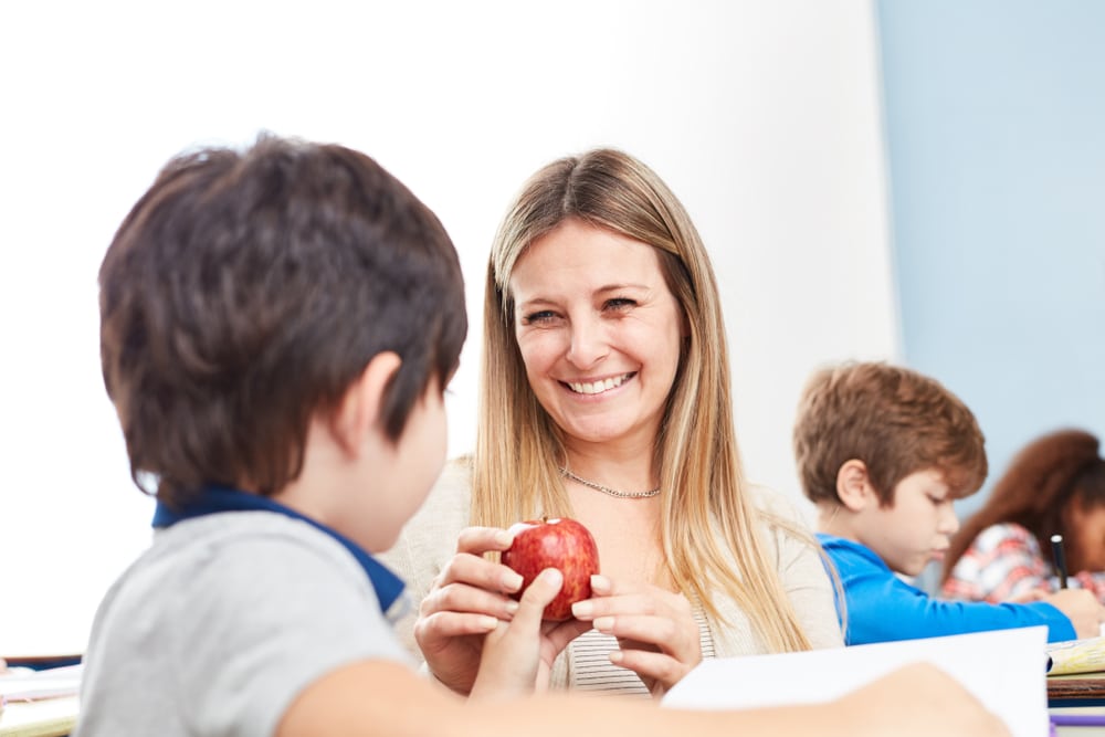 Kleiner Junge beschenkt seine Kindergärtnerin mit einem Apfel