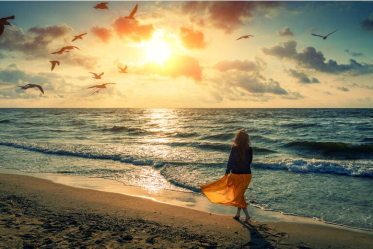 Frau geht bei Sonnenuntergang am Strand spazieren