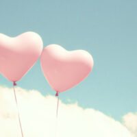 zwei rosa herzförmige Ballons am Himmel