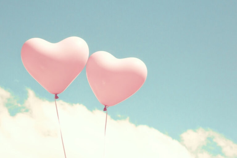 zwei rosa herzförmige Ballons am Himmel