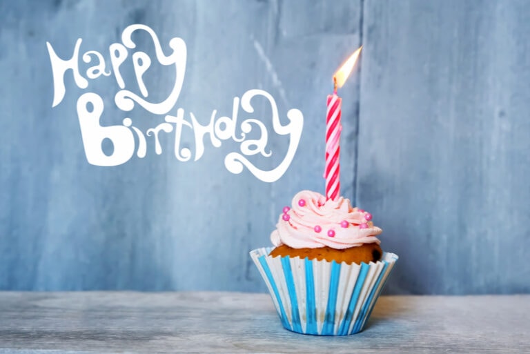 Muffin mit Kerze und einem Schild Happy Birthday