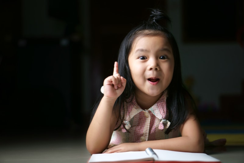 Nettes asiatisches Mädchen hält Finger mit offenem Mund hoch