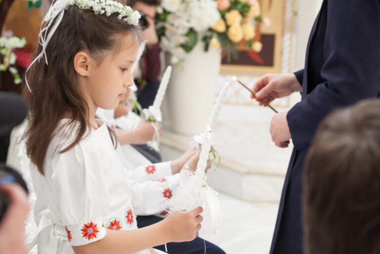 kleines Mädchen mit Kerze bei der Kommunion in der Kirche