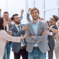 lächelnder geschäftsmann auf dem hintergrund des jubelnden geschäftsteams