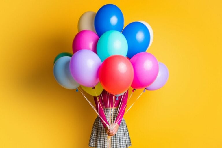 Mädchen hält bunte Geburtstagsballons