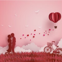 Verliebte standen auf den Wiesen und ein herzförmiger Papierballon schwebte am Himmel