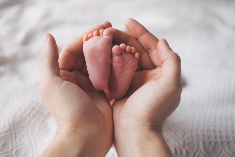 Mutter, die die Füße des Babys hält