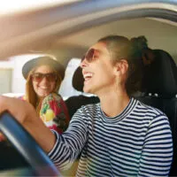 glückliche frau, die ihre freundin im auto fährt