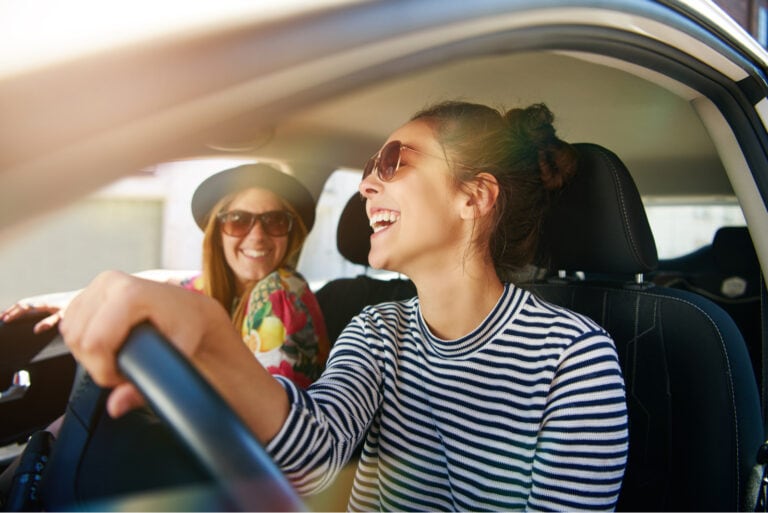 glückliche frau, die ihre freundin im auto fährt