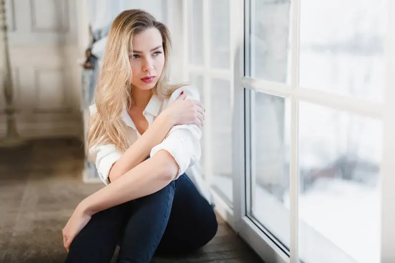 traurige junge Frau sitzt am Fenster