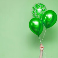 Hand hält grüne Geburtstagsballons