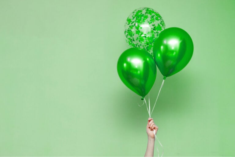 Hand hält grüne Geburtstagsballons