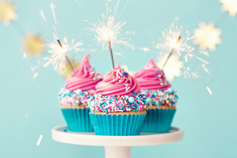 Drei Geburtstags-Cupcakes mit rosa Zuckerguss und Party-Wunderkerzen