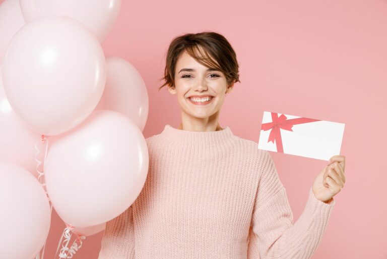 Frau lächelt und hält Geburtstagskarte und Luftballons