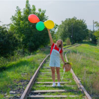 Frau springt mit Bällen auf die Eisenbahn