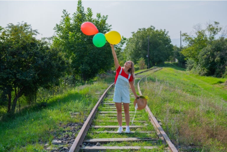 Frau springt mit Bällen auf die Eisenbahn